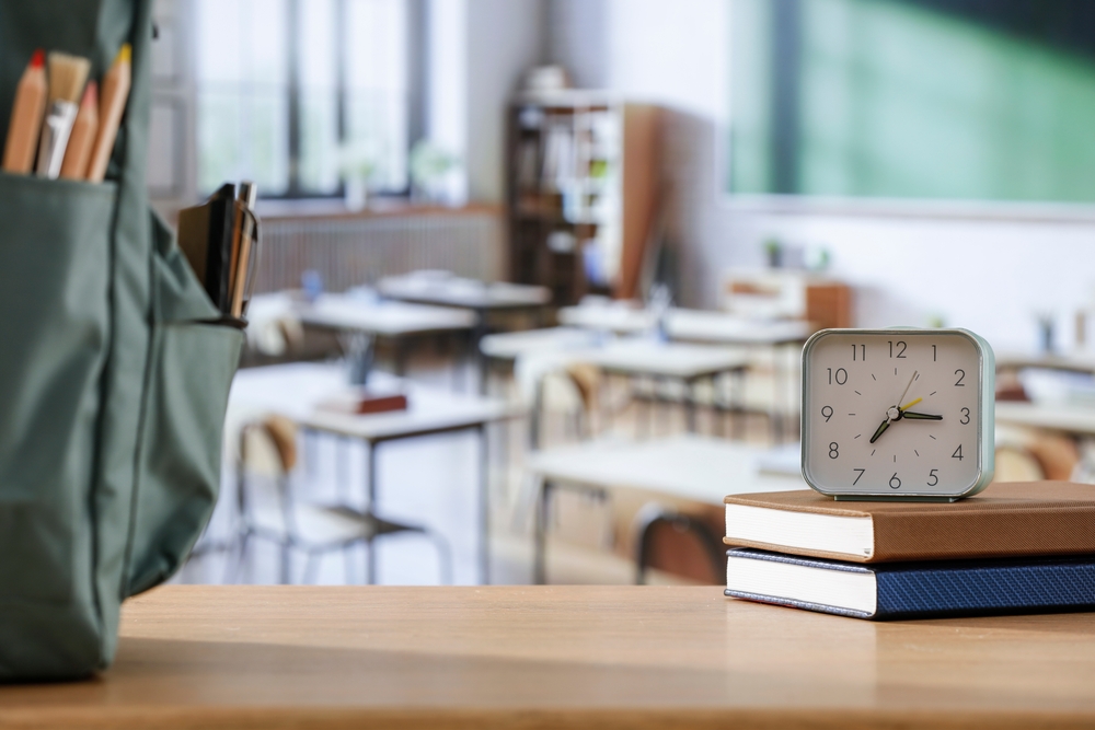 School,Supplies,And,Schoolbag,On,Wooden,School,Desk.,Blurred,Classroom